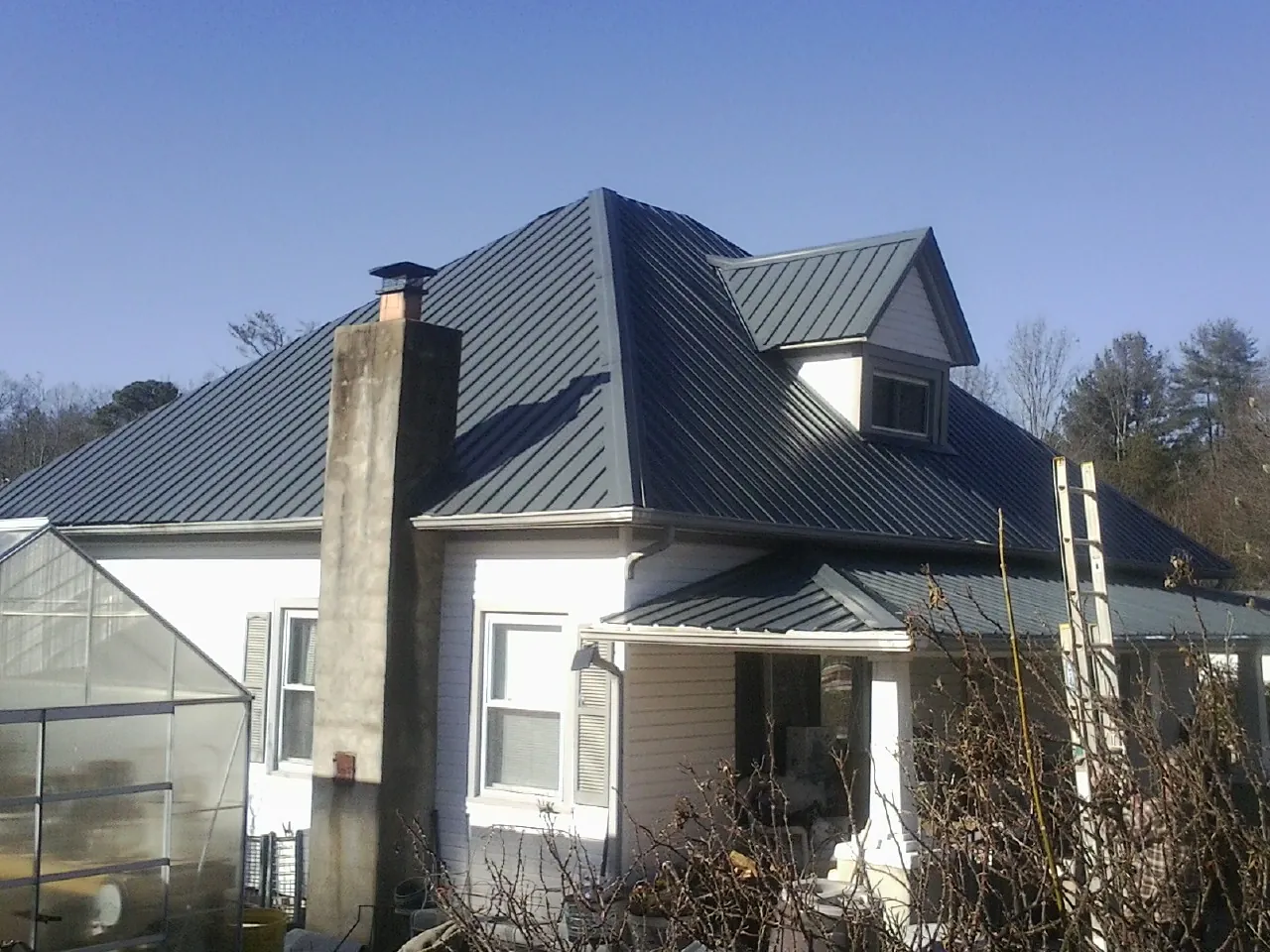 Dark blue standing seam metal roof on a white farmhouse with dormer — Slate & Tile Roof Repair by Roofing Brothers in Fort Bragg