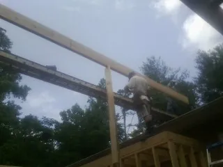 Carpenter setting a ridge beam over a new addition frame — Ice Dam Removal by Roofing Brothers in Fort Bragg