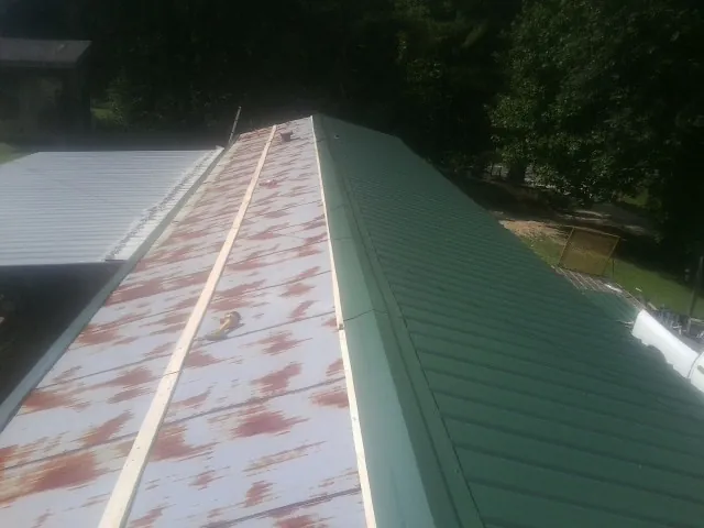 Old rusted panels beside newly installed green metal roofing — Wind Damage Roof Repair by Roofing Brothers in Fort Bragg