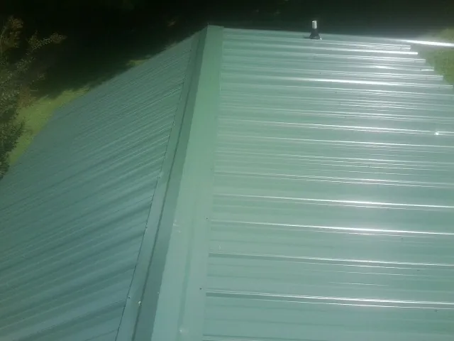 New green metal panels meeting at the ridge of a roof — Flat Roof Repair work by our crew in Fort Bragg
