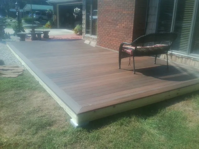 New wood deck and wicker chair beside a brick house in Fort Bragg
