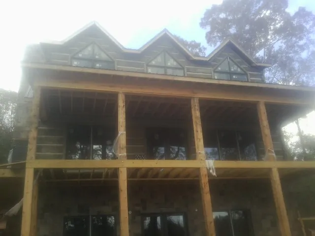 Dormers and porch framing on a large log home under construction — Roof Coating work by our crew in Fort Bragg