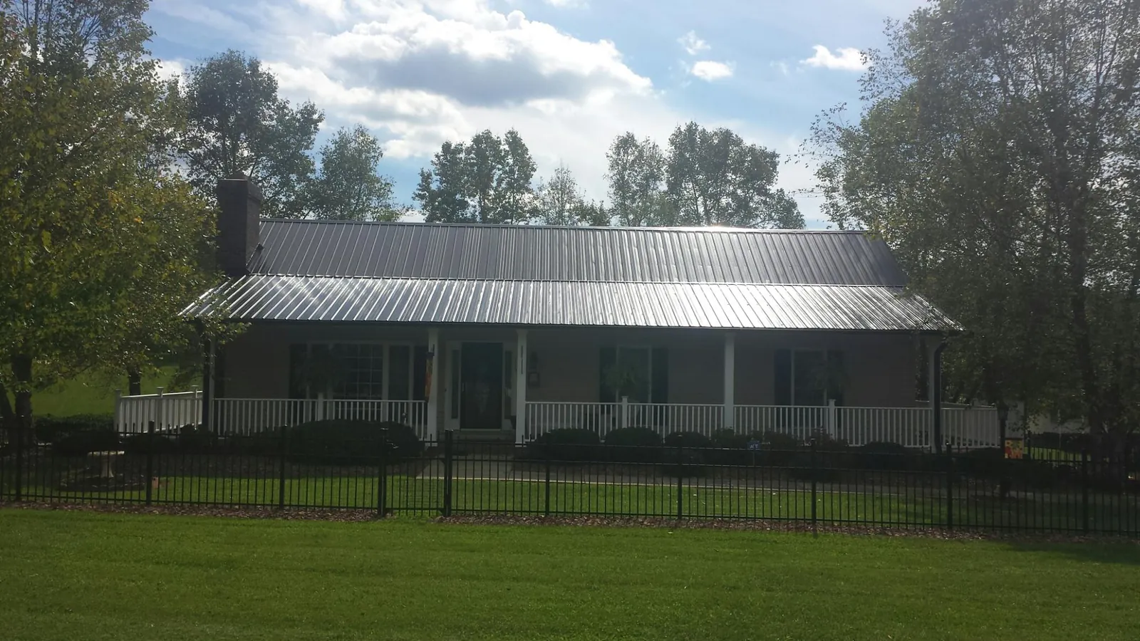 Gray metal roof on a brick ranch with a full width front porch — Gutter Guard Installation work by our crew in Fort Bragg