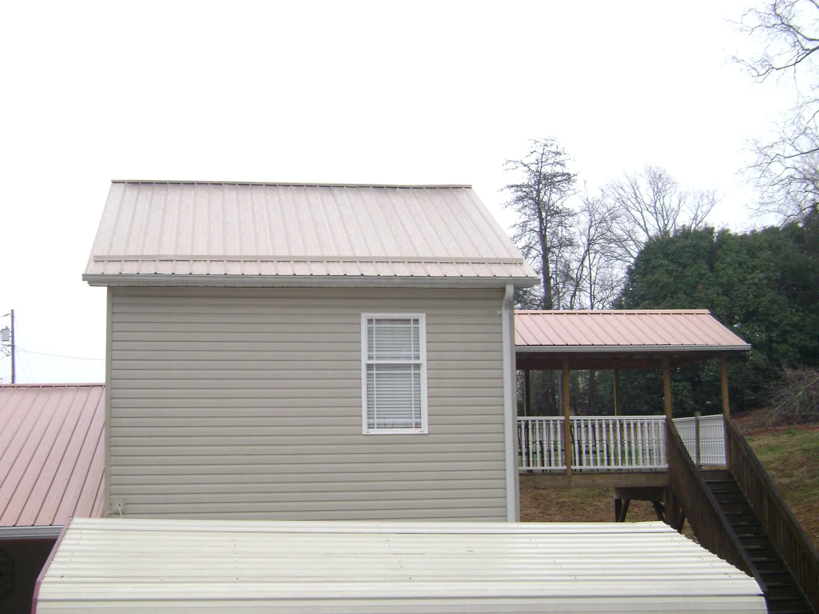 Tan metal roofs on a two story addition and attached porch, from a Roof Replacement job in Fort Bragg