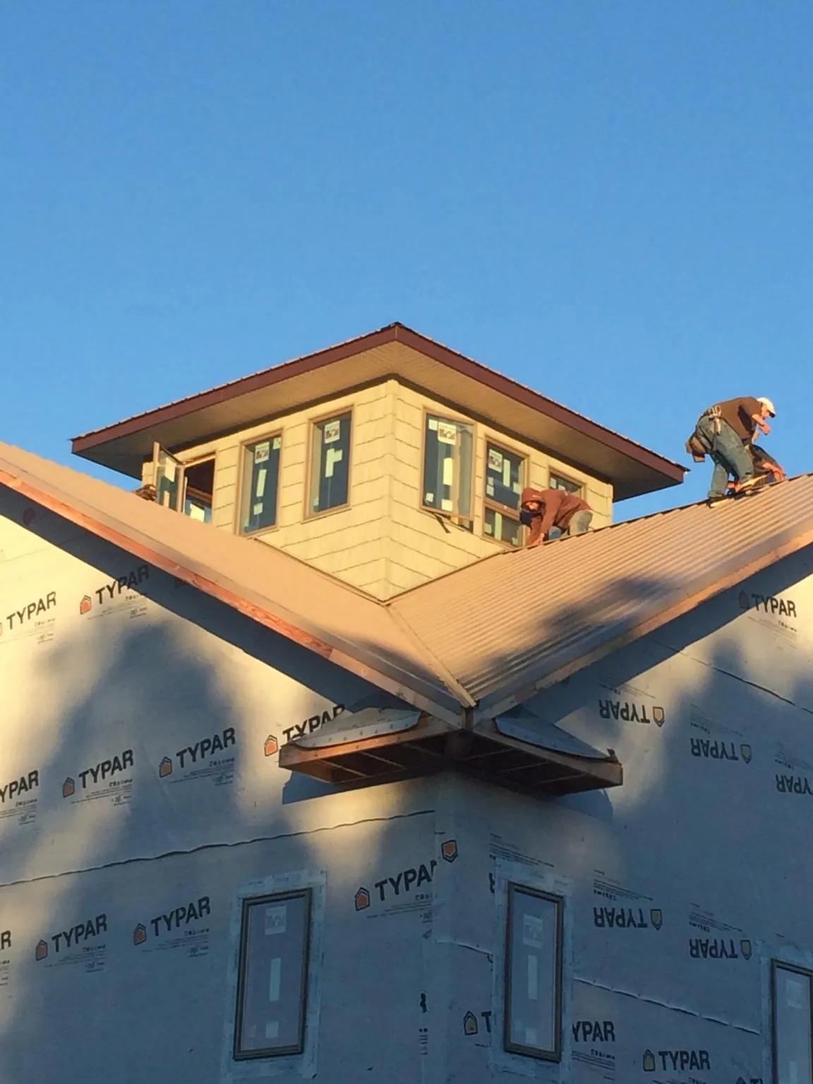 Roofers working around a rooftop cupola on a new metal roof at sunset — Roof Waterproofing in Fort Bragg by Roofing Brothers